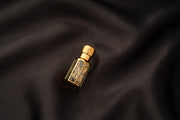 Gold perfume bottle on a dark fabric background