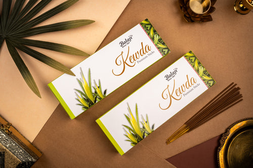 BalaJi Kewda incense packets on a brown surface with green leaves and incense sticks.